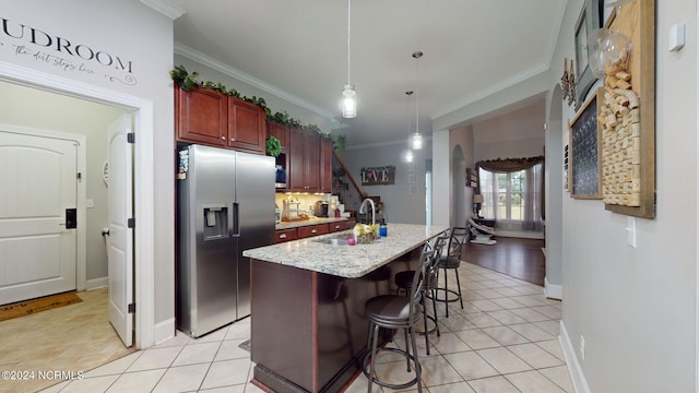 kitchen featuring sink, stainless steel fridge, hanging light fixtures, ornamental molding, and a kitchen bar