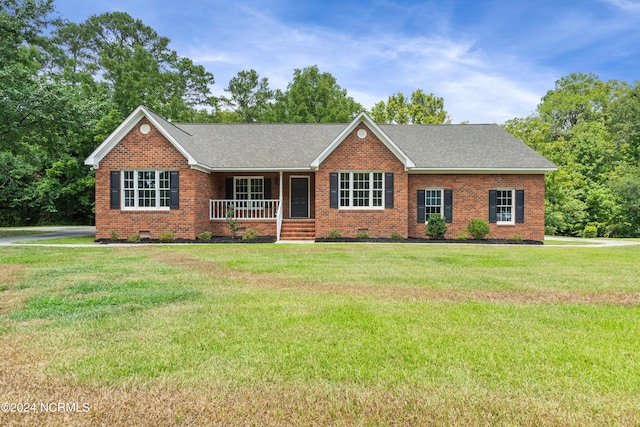 ranch-style house featuring covered porch and a front yard