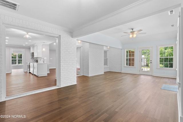 unfurnished living room featuring hardwood / wood-style floors, ceiling fan, sink, and brick wall