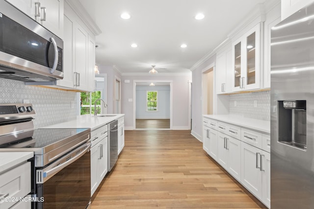 kitchen featuring sink, stainless steel appliances, crown molding, white cabinets, and light wood-type flooring