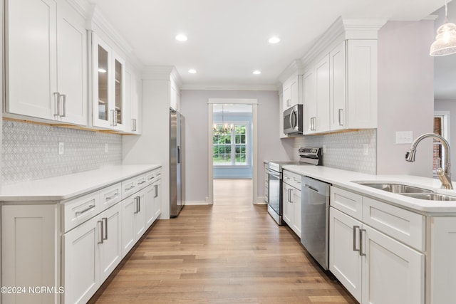 kitchen with white cabinetry, sink, ornamental molding, and appliances with stainless steel finishes