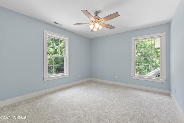 carpeted spare room featuring ceiling fan and a healthy amount of sunlight