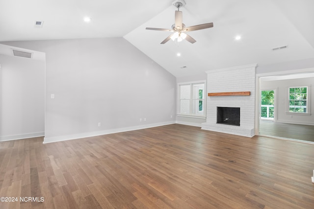 unfurnished living room with hardwood / wood-style floors, ceiling fan, vaulted ceiling, and a brick fireplace