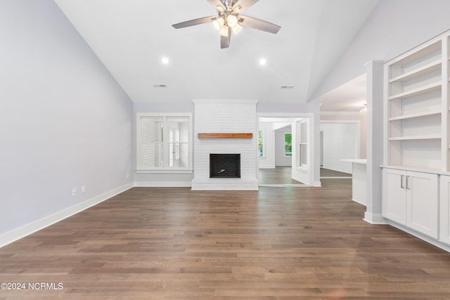 unfurnished living room featuring ceiling fan, dark hardwood / wood-style floors, vaulted ceiling, and a brick fireplace