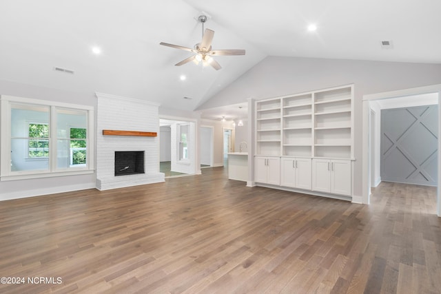 unfurnished living room with hardwood / wood-style flooring, a brick fireplace, ceiling fan, and lofted ceiling