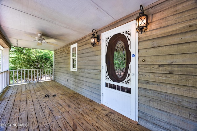 view of exterior entry with ceiling fan and a porch
