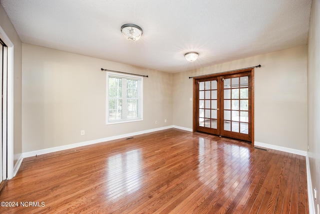 unfurnished room featuring baseboards, visible vents, french doors, and hardwood / wood-style flooring