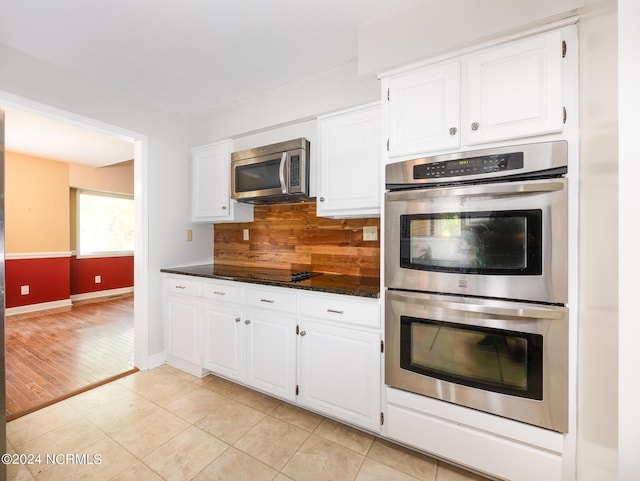 kitchen with baseboards, white cabinetry, light tile patterned floors, appliances with stainless steel finishes, and backsplash