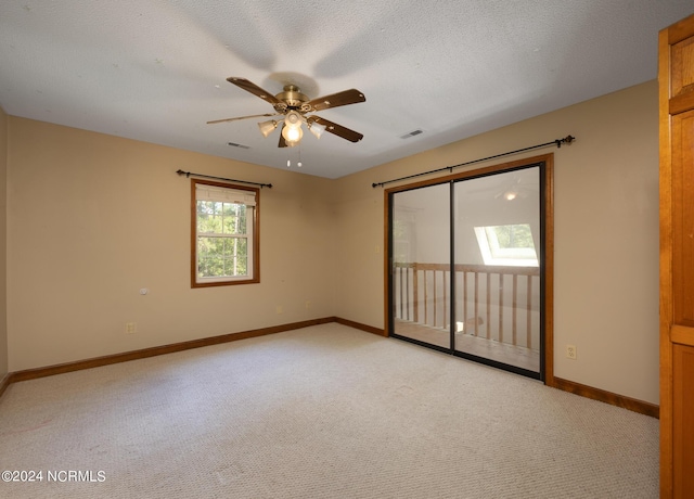spare room featuring light colored carpet, a ceiling fan, visible vents, and baseboards
