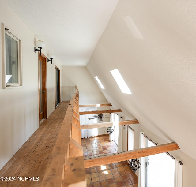 corridor featuring lofted ceiling with skylight and an upstairs landing