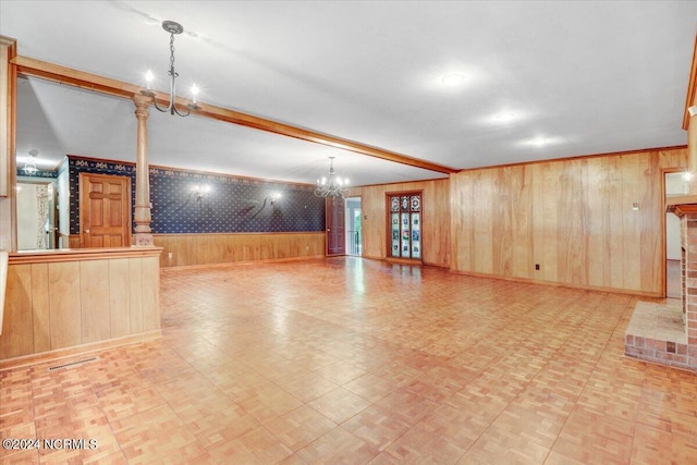 unfurnished living room featuring beamed ceiling, light parquet flooring, an inviting chandelier, and wood walls