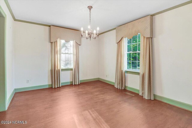 spare room featuring crown molding, hardwood / wood-style flooring, and a chandelier