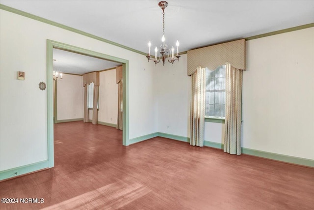 spare room featuring crown molding, wood-type flooring, and a chandelier