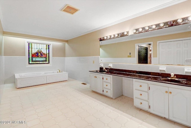 bathroom with vanity, a tub, ornamental molding, and tile walls