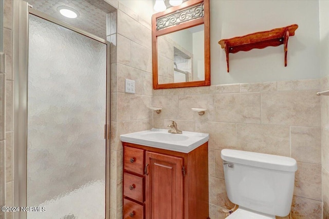 bathroom featuring vanity, toilet, a shower with door, and tile walls