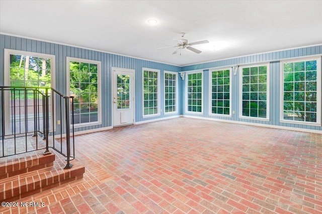 unfurnished sunroom featuring ceiling fan and a healthy amount of sunlight