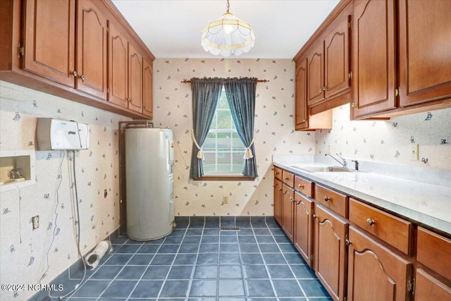 clothes washing area with cabinets, electric water heater, sink, and dark tile patterned floors