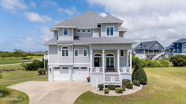 view of front of property with covered porch, a front yard, and a garage