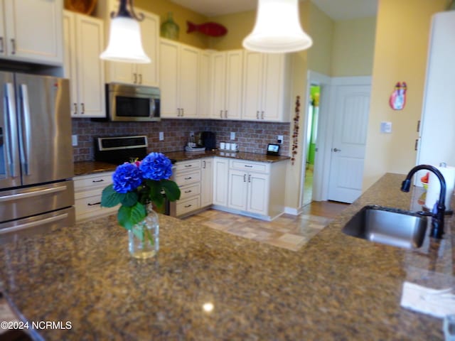 kitchen featuring decorative backsplash, sink, white cabinets, and appliances with stainless steel finishes