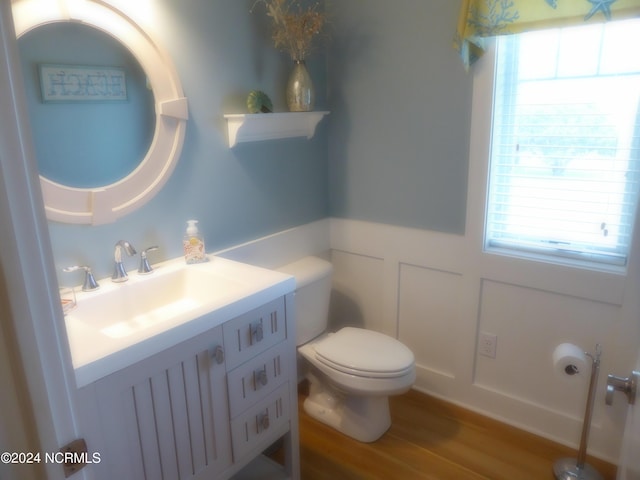 bathroom featuring hardwood / wood-style flooring, vanity, a healthy amount of sunlight, and toilet