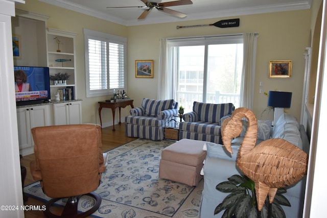 living room with light hardwood / wood-style floors, ceiling fan, and ornamental molding