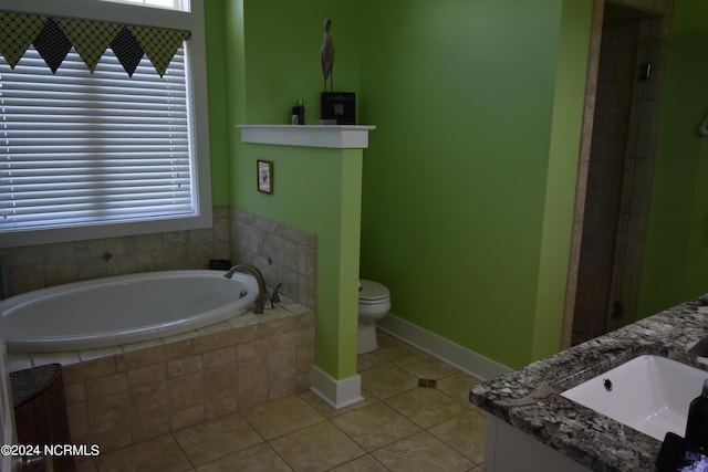 bathroom with tile patterned flooring, vanity, toilet, and tiled bath