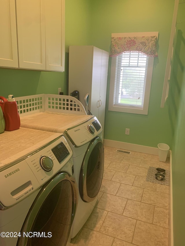 clothes washing area featuring separate washer and dryer and cabinets