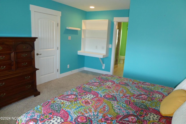 bedroom featuring ensuite bathroom and light carpet