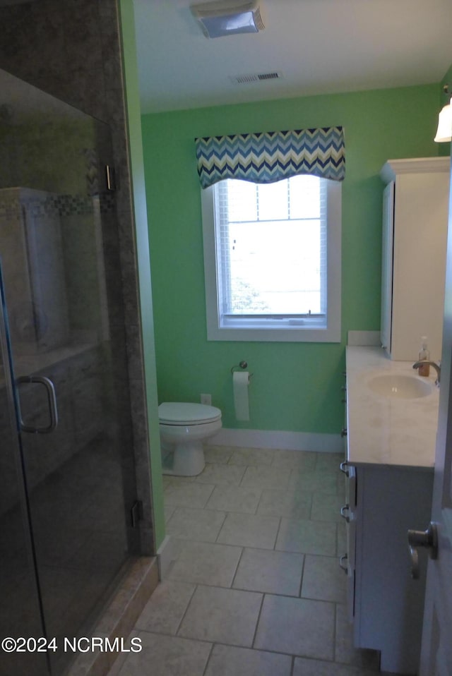 bathroom featuring tile patterned floors, a shower with door, vanity, and toilet