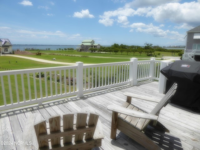 wooden deck with a lawn, a grill, and a water view