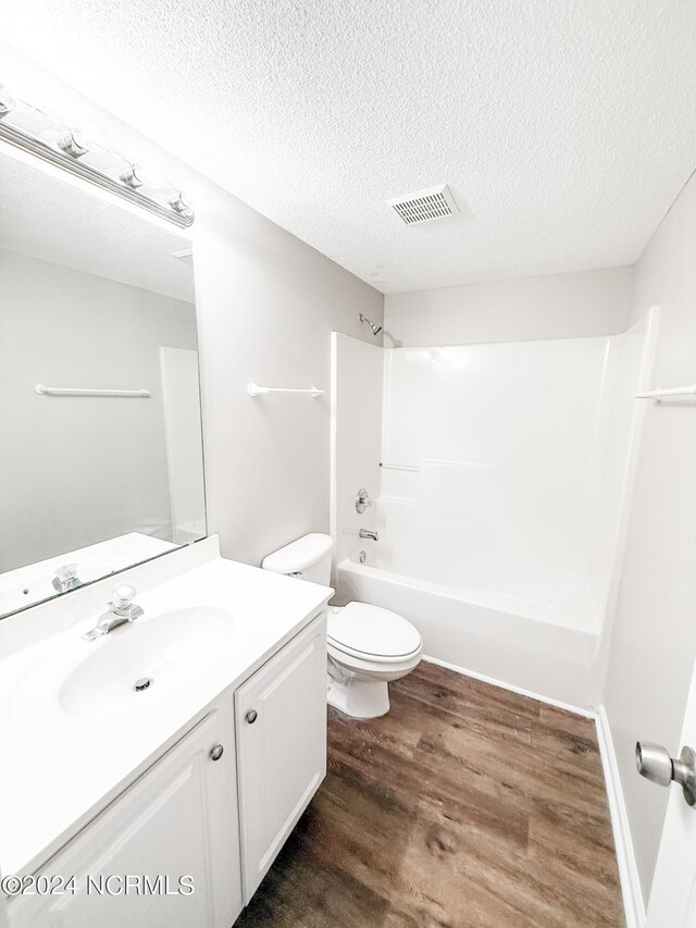 full bathroom featuring a textured ceiling, toilet, shower / bath combination, vanity, and hardwood / wood-style flooring