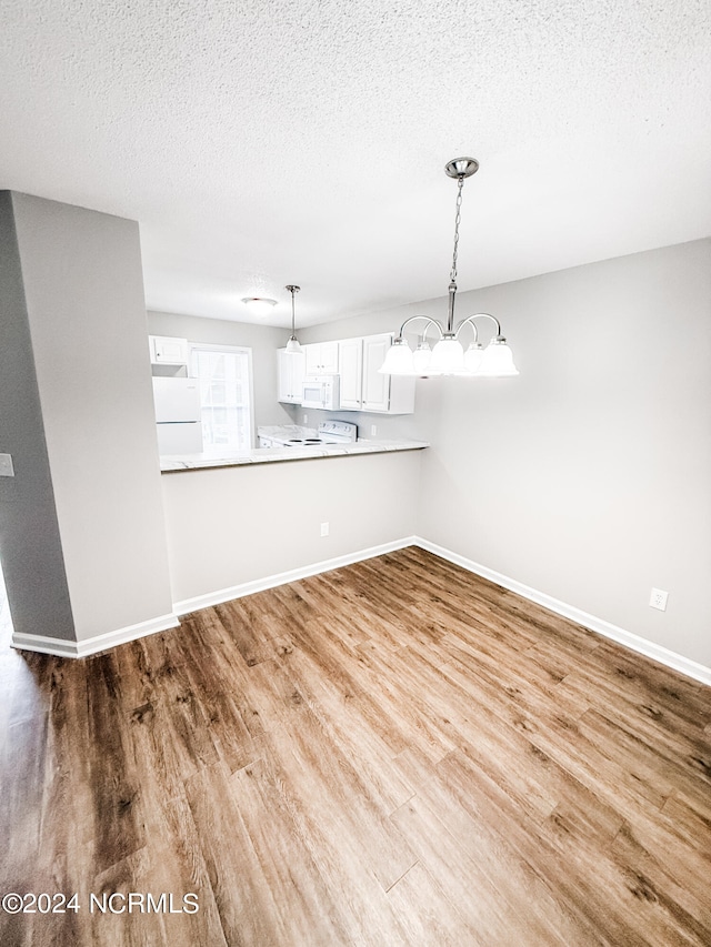 interior space with hanging light fixtures, kitchen peninsula, light wood-type flooring, white cabinetry, and white appliances