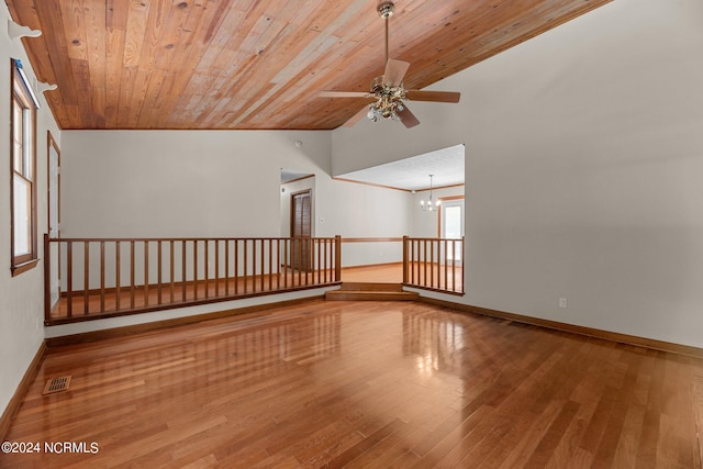 empty room with wood ceiling, wood-type flooring, ceiling fan with notable chandelier, and vaulted ceiling