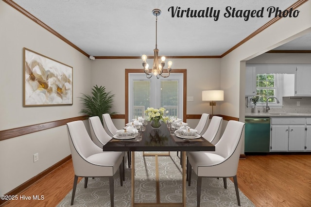 dining space with an inviting chandelier, sink, hardwood / wood-style flooring, and crown molding