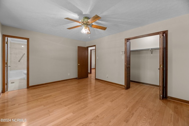 unfurnished bedroom featuring ensuite bath, light hardwood / wood-style flooring, a closet, and a textured ceiling