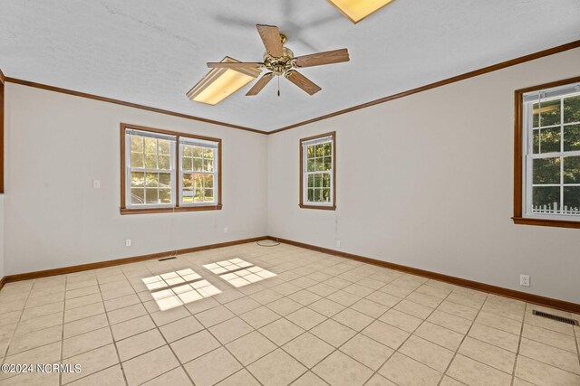 tiled spare room with ceiling fan, ornamental molding, a textured ceiling, and plenty of natural light