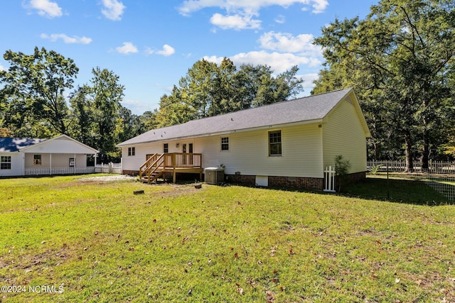 rear view of house featuring a wooden deck, central AC unit, and a lawn