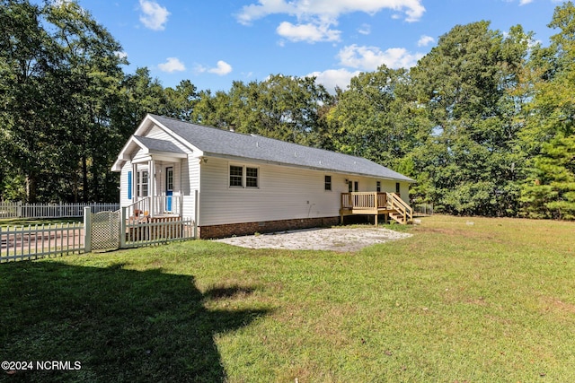 back of property featuring a wooden deck and a lawn