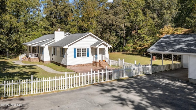 view of front facade featuring a chimney, aphalt driveway, a fenced front yard, a shingled roof, and a front lawn