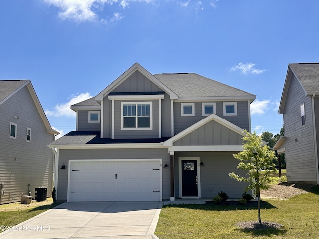 view of front of house with a garage, a front yard, and central AC