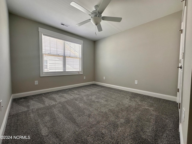 unfurnished room featuring visible vents, dark carpet, baseboards, and ceiling fan