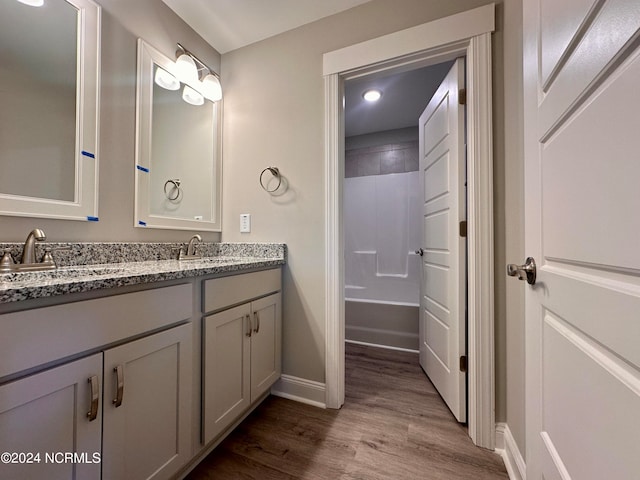 bathroom featuring double vanity, a sink, baseboards, and wood finished floors