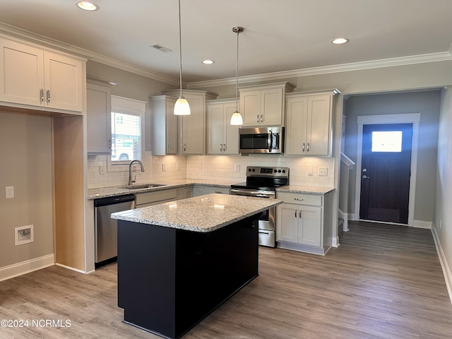 kitchen with stainless steel appliances, a kitchen island, a sink, visible vents, and light wood-type flooring