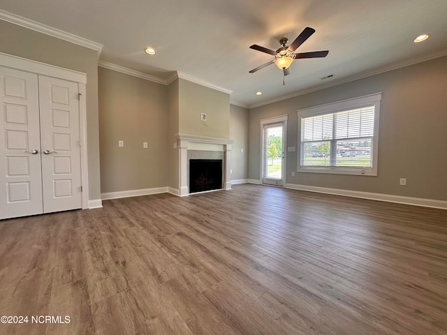 unfurnished living room with visible vents, baseboards, wood finished floors, crown molding, and a fireplace