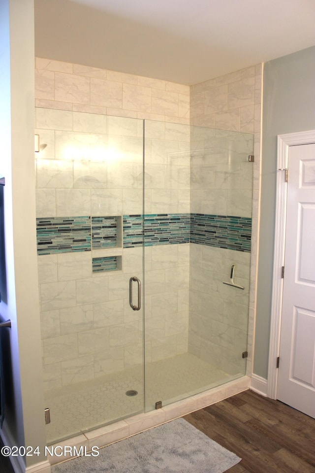 bathroom with a shower with shower door and wood-type flooring