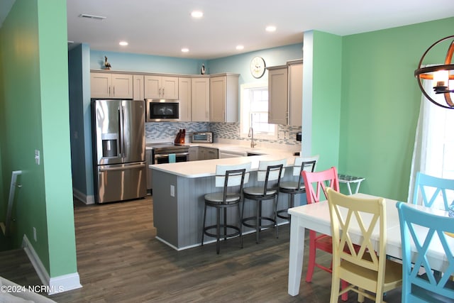 kitchen featuring kitchen peninsula, decorative backsplash, dark hardwood / wood-style floors, and stainless steel appliances