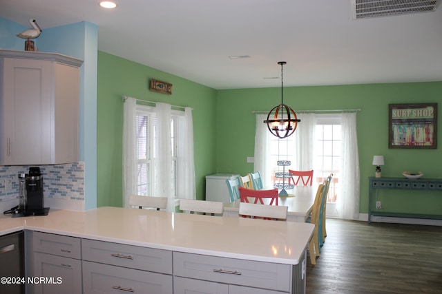 kitchen with a notable chandelier, dishwashing machine, tasteful backsplash, dark hardwood / wood-style floors, and hanging light fixtures