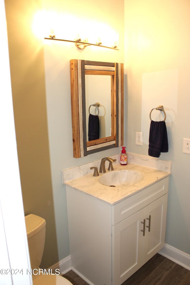 bathroom with hardwood / wood-style floors, toilet, and vanity