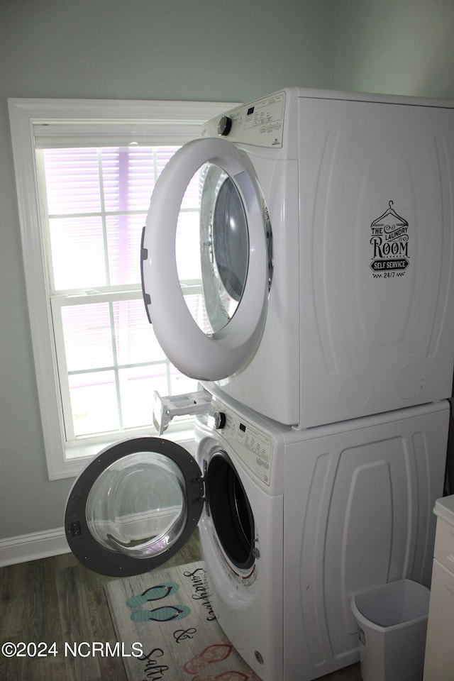 laundry room with hardwood / wood-style flooring, stacked washer / drying machine, and a wealth of natural light