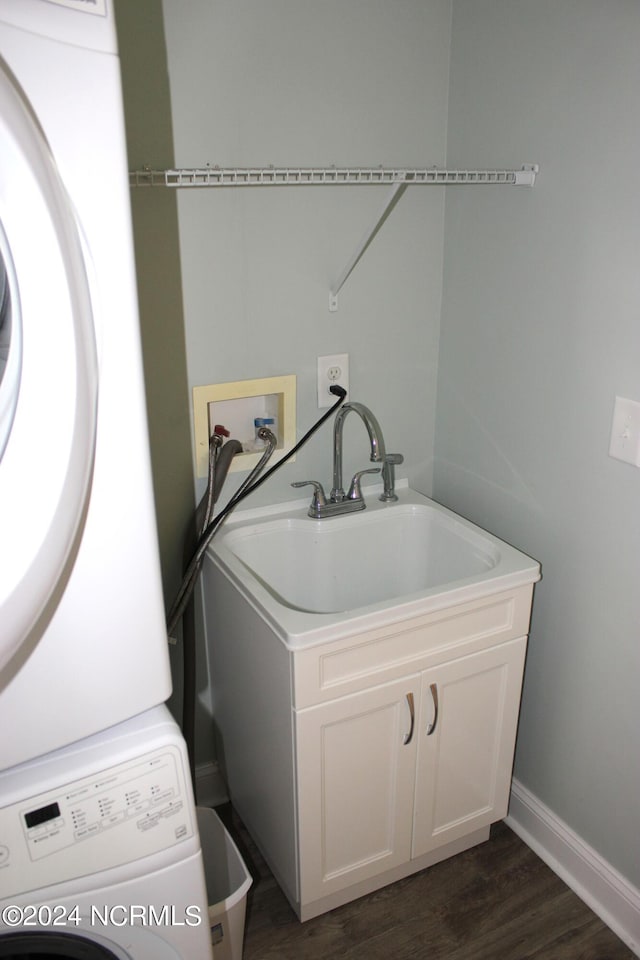 washroom with dark wood-type flooring, cabinets, and stacked washing maching and dryer